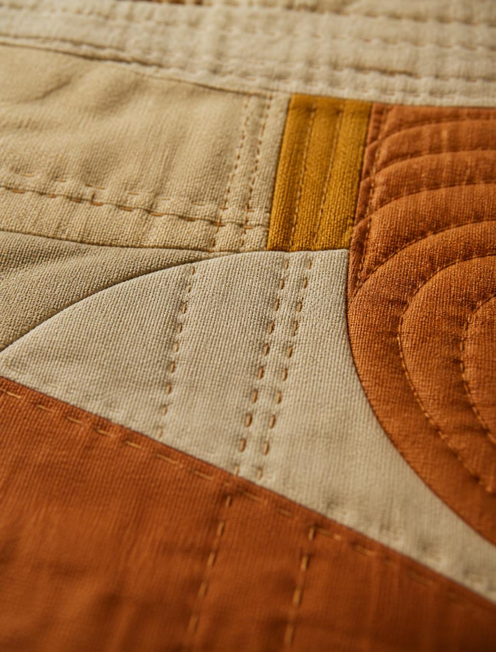 Macro detail of hand quilting in linen and clay tones